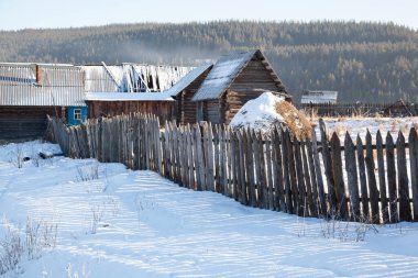 Kışın dağların arasında bir köy. Evler, barakalar, saman yığınları.