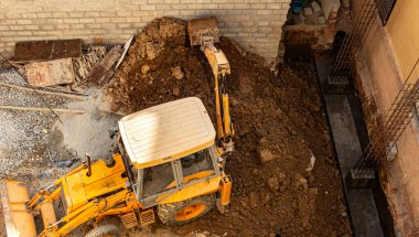 Bir inşaat sahasında kil toprağı taşıyan makineler çalışıyor.