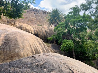 Thirumayam Kalesi 'nde bulutlu gökyüzüne karşı palmiye ağaçları olan devasa yamaçlar, Tamil Nadu' nun Pudukkottai bölgesinde 17. yüzyıldan kalma bir tepe kalesi.