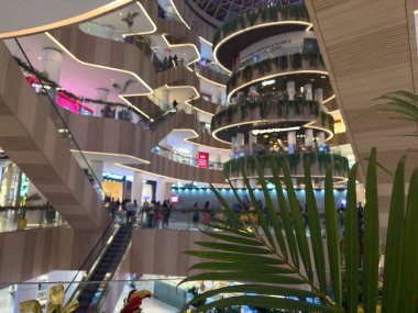 Bengaluru, Karnataka, Hindistan - 31 Aralık 2025: Bengaluru 'da kıvrımlı yürüyen merdivenler, çoklu seviyeler, çağdaş mimari ve palmiye bitkileriyle modern alışveriş merkezi içi.
