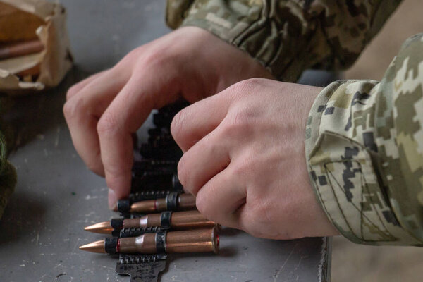 A soldier operator equips a machine-gun belt with live ammunition for the Kalashnikov machine gun. Shooting and training for battle concept