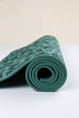 Üzerinde çiçekler ve yapraklar olan yeşil yoga minderi yere yuvarlanmış. Kaygan olmayan yoga ve egzersiz için pilates minderi.