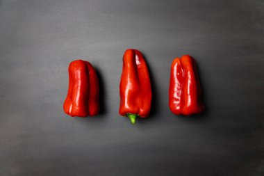 Siyah arkaplanda üç kırmızı biber ve fotokopi alanı. Renkli sebzeler, yemek malzemeleri.