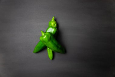 Siyah arka planda bir sürü yeşil biber var. Renkli sebzeler, yemek malzemeleri.