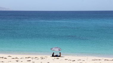 Cortes Denizi kıyısında bir plaj şemsiyesi altında iki siluet, Punta Arena de La Ventana, BCS, Meksika - 1 Mayıs 2021