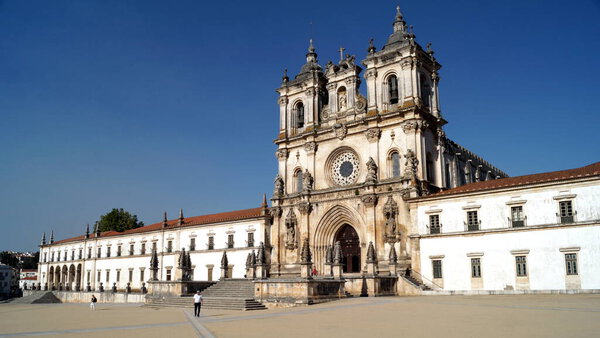 Alcobaca Monastery, built in Gothic and Baroque styles, view of the western facade facing the Praca 25 de Abril, Alcobaca, Portugal - August 8, 2016