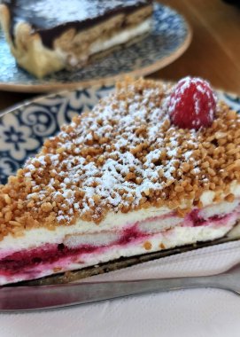 Süslü mavi ve beyaz tabakta bir dilim ahududu peynirli kek.