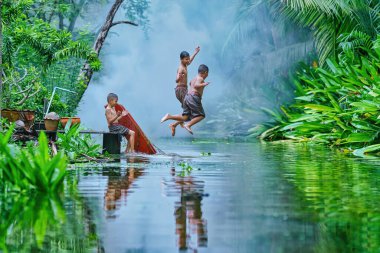 Tayland 'ın ünlü turistik beldesi Tha kha, Samut Songkhram' da kanala atlayan üç Taylandlı çocuk.