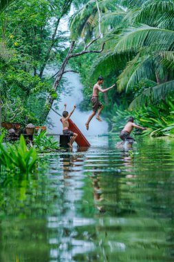 Tayland 'ın ünlü turistik beldesi Tha kha, Samut Songkhram' da kanala atlayan üç Taylandlı çocuk.