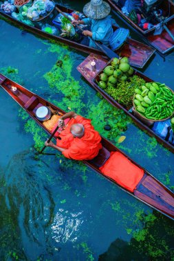 Kanalda kürek çeken küçük ahşap bir teknede Budist keşiş sabahları köylülerden yiyecek alıyor. Budist keşiş, Takha kanalı üzerinde ahşap bir teknede, Tayland 'da popüler bir turizm merkezi.