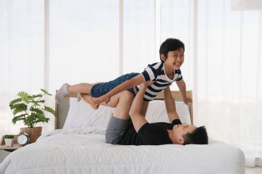 Asyalı baba ve oğlu evde yatakta oynarken iyi vakit geçiriyorlar. Baba oğul ilişkisi ve baba günü kavramı