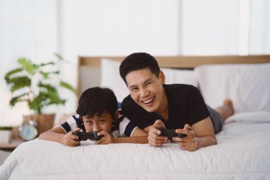 Baba ve oğul evde yatakta Vdo oynarken iyi vakit geçiriyorlar. Baba-oğul ilişkisi ve Babalar Günü kavramı