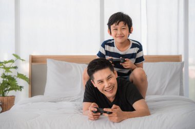 Baba ve oğul evde yatakta Vdo oynarken iyi vakit geçiriyorlar. Baba-oğul ilişkisi ve Babalar Günü kavramı