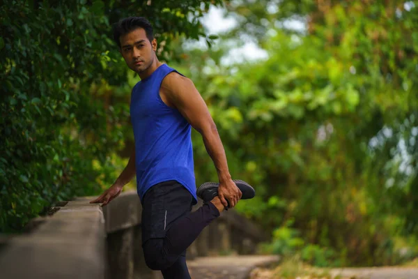 asian young athletic sport man having relax and leg stretching after jogging workout outdoors in park in morning. concept of athletic sport people lifestyle. concept of athletic sport people lifestyle