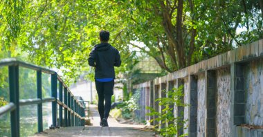 Spor giyim bölümünde sporcu spor adamı sabah parkta yol boyunca koşu antrenmanı yapıyor. Atletizm sporu insanların yaşam tarzı