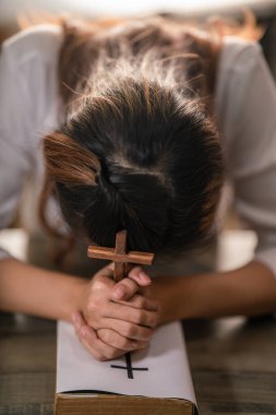 Ahşap haçın Hıristiyanlık geçmişi Tanrı 'nın lütfu için dua eden kadının ellerinde.