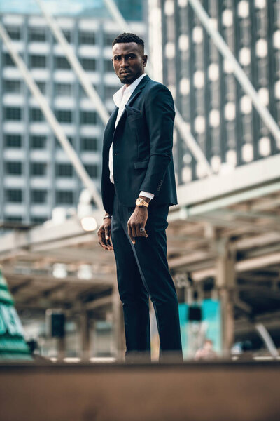 портрет успеха и уверенный в себе африканский бизнесмен на открытом воздухе позирует в современном городе.
