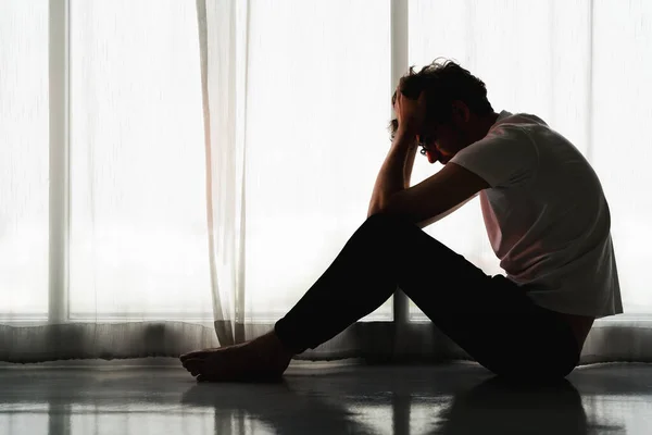 Beyaz adamın siluet dramatik portresi evde tek başına oturmuş umutsuzca beslenen ve işsizlikten depresyona giren kedere bakıyor.