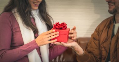 Bulanık gülen yüzlü bir kadının eli, şaşırmış bir adamdan hediye alır. Çiftler yıldönümlerini hediyeyle kutlar.