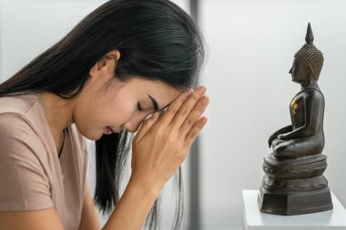 Dindar Asyalı Budist kadın evinde Buda heykeline inançla ibadet ediyor ve dua ediyor.