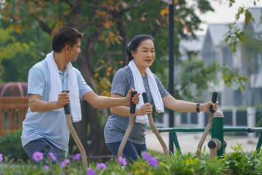 Parkta egzersiz yaptıktan sonra esneme hareketleri yapan Asyalı bir çiftin spor ve egzersiz geçmişi.