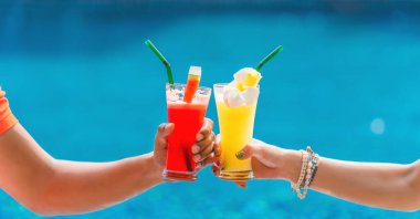 yaz ve tropikal içecek arka planda meyve suyu karpuz ve ananas çiftin ellerinde tatil köyü ve otelde turkuaz mavi havuz