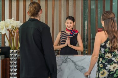 Otel resepsiyonistine hoş geldiniz. Tayland wai 'li beyaz bir çift ve otel resepsiyonuna vardıktan sonra gülümseyin.