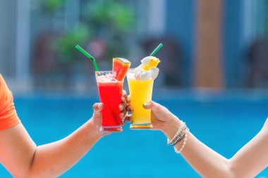yaz ve tropikal içecek arka planda meyve suyu karpuz ve ananas çiftin ellerinde tatil köyü ve otelde turkuaz mavi havuz