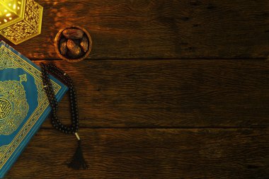 Kutsal Kur 'an' ın arka planında tahtadan bir masa üzerinde tarihi, tespih ve Arap feneri, Arapça el yazısı anlamına gelen kutsal Kur 'an kitabı.