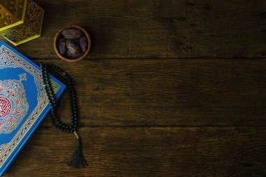 Kutsal Kur 'an' ın arka planında tahtadan bir masa üzerinde tarihi, tespih ve Arap feneri, Arapça el yazısı anlamına gelen kutsal Kur 'an kitabı.