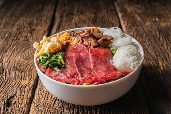 vietnam food background of bowl of vietnamese pho rice noodle with sliced fresh beef and stewed beef on wooden table