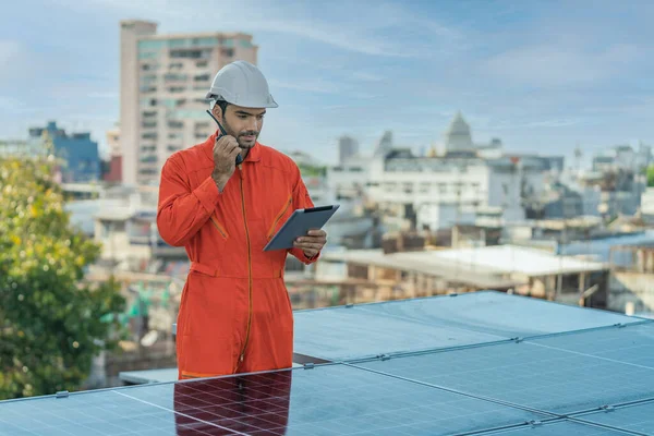 portrait of caucasian alternative energy engineer with tablet computer using communication radio checking energy power performace of solar rooftop system installed of plant rooftop