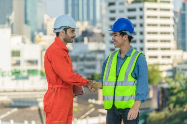 Kafkasyalı baş mühendis ve Asyalı elektrikçi, kentteki şantiyede çalıştıktan sonra el sıkışmışlar.