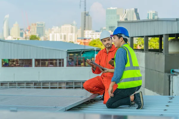 caucasian and asian service and maintenance engineering team for solar rooftop system checking energy performance of solar cell panels installed on plant rooftop