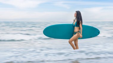 Yaz tatilinde sörf yapmak için deniz kenarında sörf tahtası olan Asyalı güzel bir sörfçü. Plajda yaz tatili aktivitesi kavramı