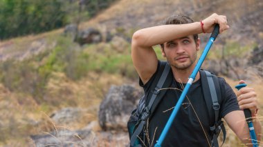 caucasian backpack hiker with trekking stick walking on trekking trail on mountain on summer sport journey leisure