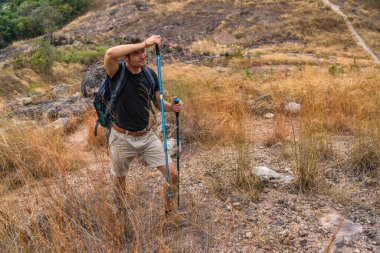 caucasian backpack hiker with trekking stick walking on trekking trail on mountain on summer sport journey leisure