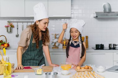 Asyalı anne ve küçük kızı evde birlikte fırın yaparken eğleniyorlar.