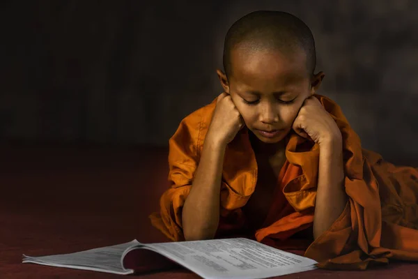 身着橙色长袍的泰国初学者肖像画躺在地板上看书佛教减少了寺庙里的书籍 佛教时期佛教初学者的佛教观念有所减弱 — 图库照片