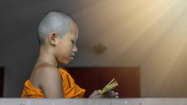 オレンジの衣を着たタイ仏教の初心者の肖像画が立って仏教を読むと 寺院の窓による聖書の減少します 仏教の初心者の勉強仏教の期間中に減少します — ストック写真