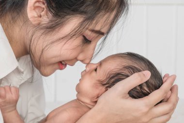 Güzel annenin yeni doğmuş bebeğini mutlu yüzüyle kucağına aldığı portreyi yakından çek.