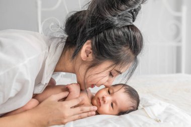Seçici odaklanmış. Yeni doğmuş bebek portresi. Annesi el ele tutuşmuş şekilde yatakta yatıyor.