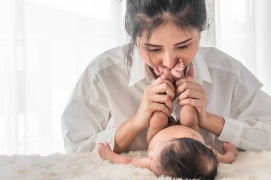 Seçici odaklanmış güzel annenin portresi. Yeni doğmuş bebeğinin ayaklarını tutuyor ve sevgiyle bakıyor.