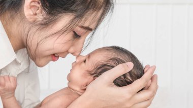 Güzel annenin yeni doğmuş bebeğini mutlu yüzüyle kucağına aldığı portreyi yakından çek.