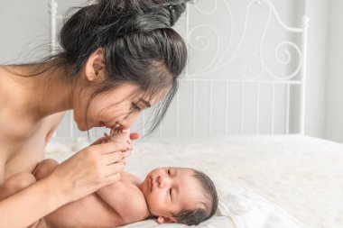 Seçici odaklanmış. Yeni doğmuş bebek portresi. Annesi el ele tutuşmuş şekilde yatakta yatıyor.