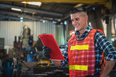 Fabrika müfettişinin endüstri geçmişi ayakta ve listedeki kontrol panolarını tutuyor fabrikadaki bakım işlerini kontrol ediyor.