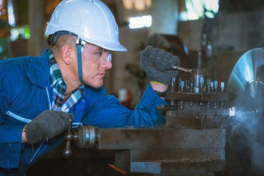 Metal atölyesi ve fabrikasında metal parçası yapmak için makine işleten makine mühendisinin portresinin endüstriyel arka planı