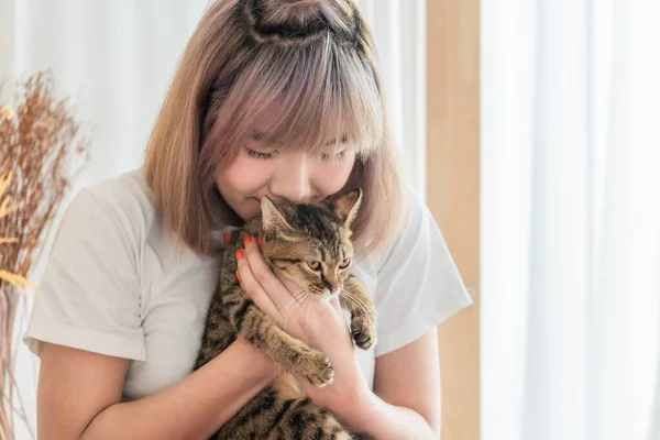 young asian woman playing with cat in living room at home