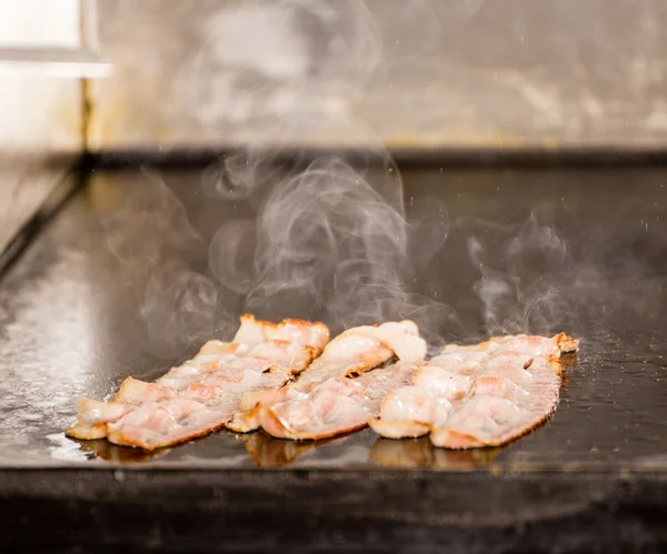 Fechar as tiras de bacon fritas saborosas no painel de grelhar — Fotografia de Stock