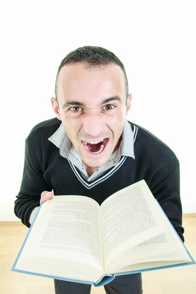 Angry young man holding a book tired of reading — Stock Photo, Image